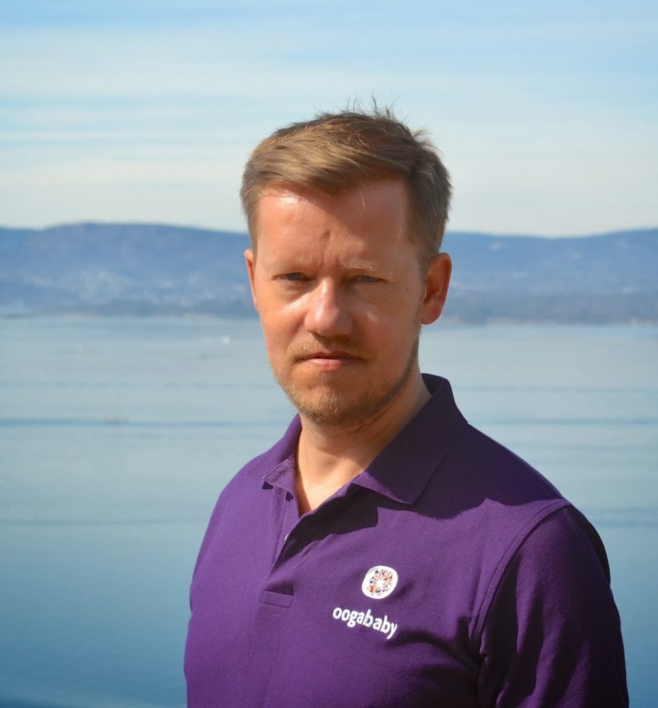 Portrettbilde av Klaus Damlien,  leder markedsføring og digitale kanaler i Redd Barna. Han har på seg lilla t-skjorte og står med havet som bakgrunn. 