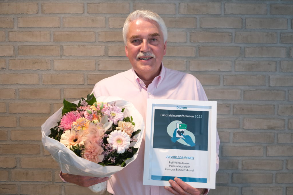 Leif Wien Jensen i Norges Blindeforbund. Har står med en blomsterbukett og et diplom for prisen Juryens spesialpris.