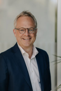 Portrettbilde av Øystein Eriksen Søreide, Administrerende direktør i Abelia. Han har på seg hvit skjorte og mørkeblå blazer.